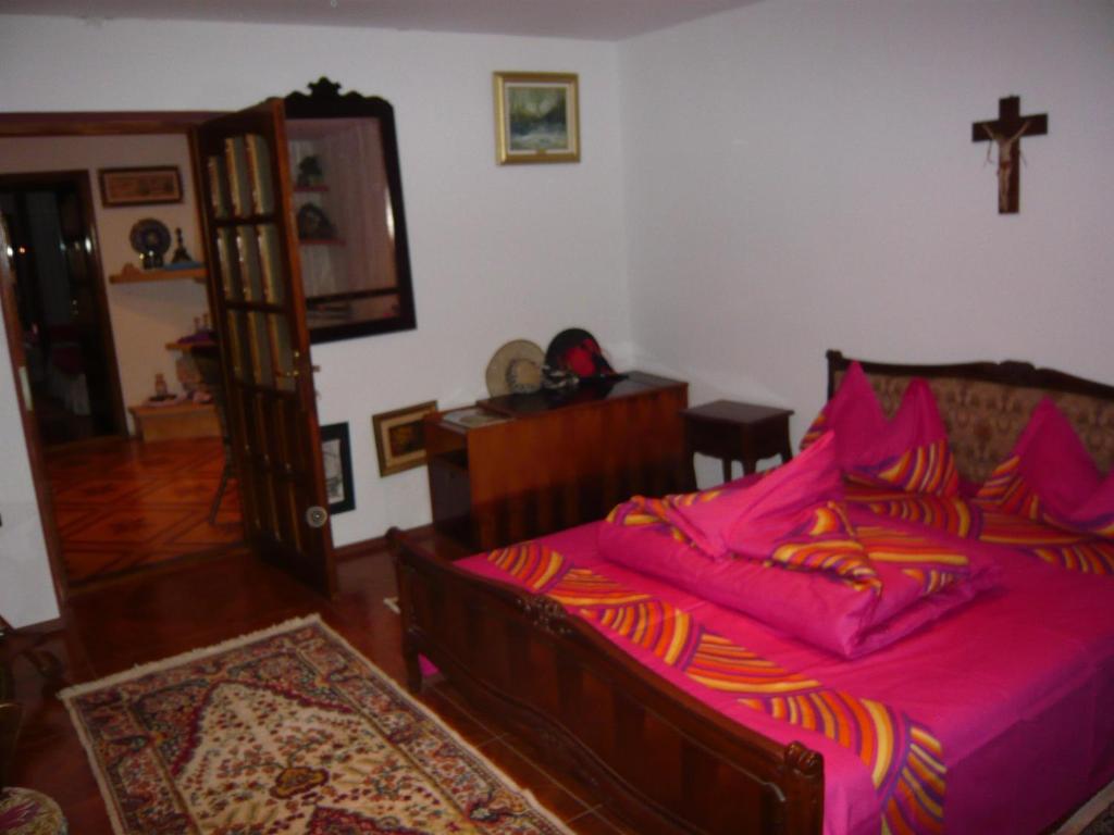 una camera da letto con un letto con lenzuola rosa e una croce sul muro di Casa de Vacanta Pravdencu a Mahmudia