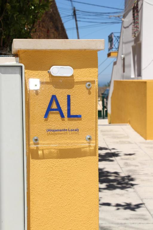 una caja amarilla con un letrero al al costado de una acera en Vina's Place, en Nazaré