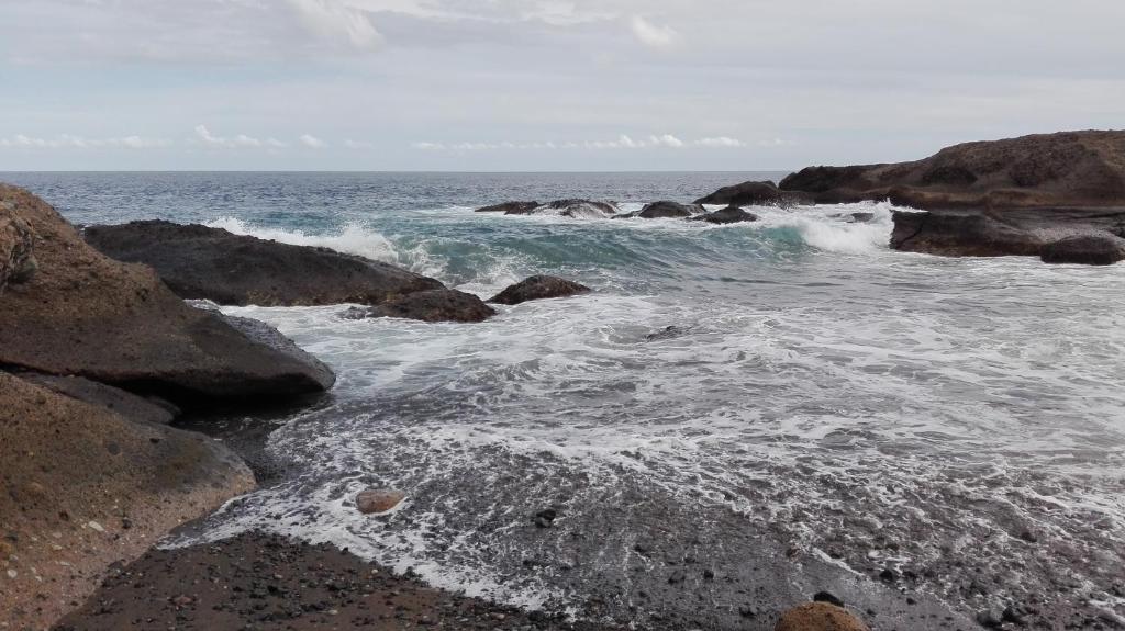 a beach with rocks and the ocean with waves at Casa Mary in Granadilla de Abona