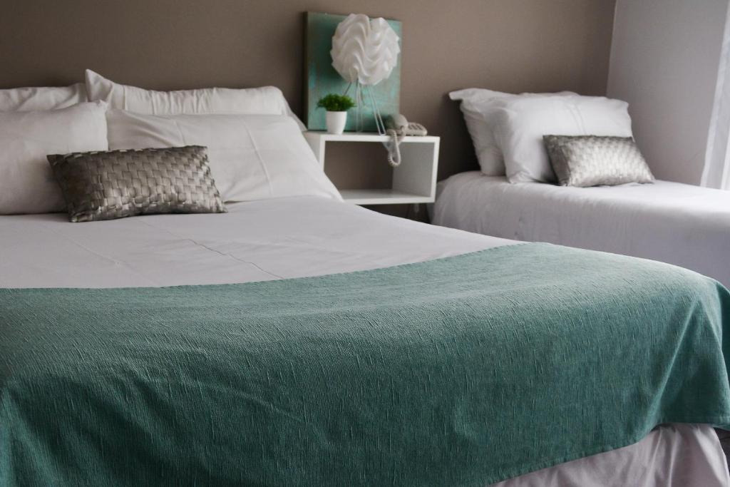 a bedroom with two beds with green sheets at Argenta Apart Hotel in Trelew