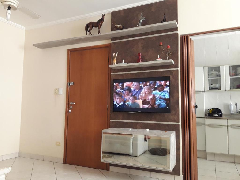 a living room with a tv on a wall at Apto no Ed. Alexandra I in Guarujá