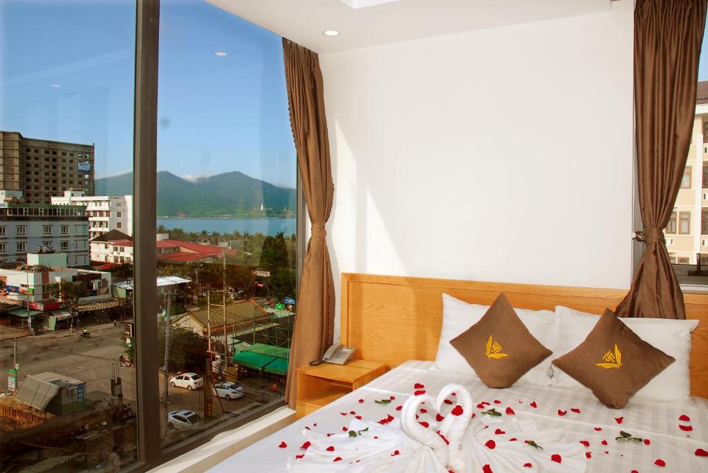 a bedroom with a bed and a large window at Trang Ngan Hotel by THG in Danang