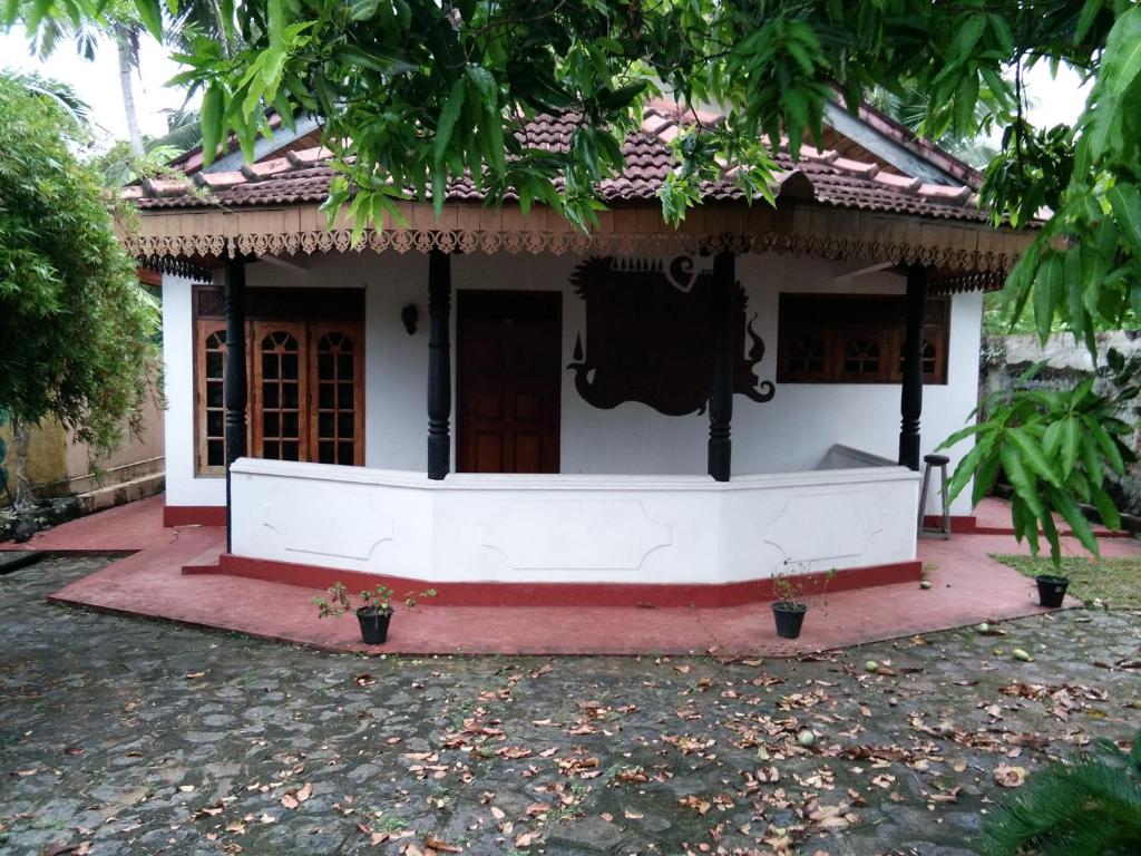 a small white house with a red floor at Villa O.V.C in Hikkaduwa