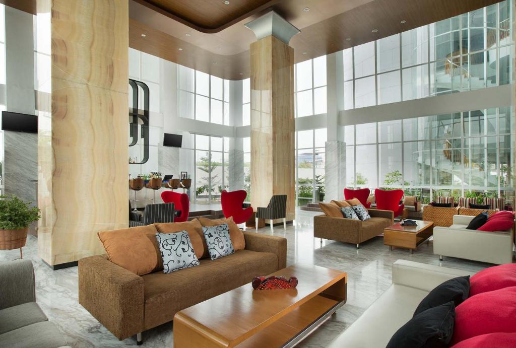 a living room with couches and tables in a building at Hariston Hotel&Suites, Pluit - Jakarta in Jakarta