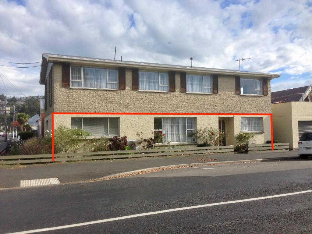 um edifício ao lado de uma rua com um carro à frente em Big & Bright Guest House em Dunedin