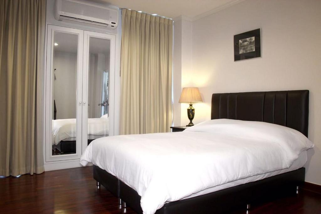 een slaapkamer met een groot wit bed en een raam bij Samsen Suites/ 2 Br Suites for less in Bangkok