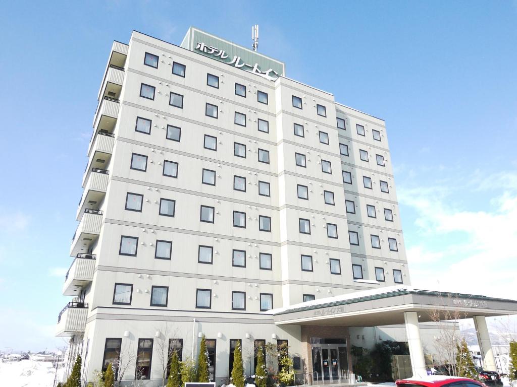 Un bâtiment blanc avec un panneau en haut dans l'établissement Hotel Route-Inn Odate Omachi, à Ōdate