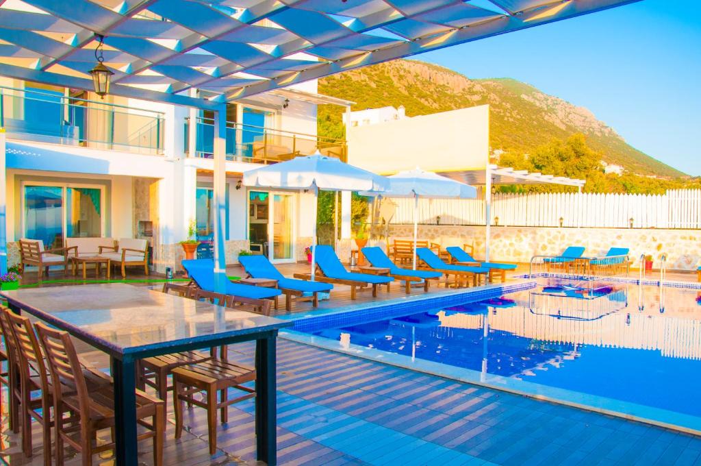 a pool with chairs and umbrellas at a resort at Villa Erdo Kalkan 5 Bedroom Villa in Kalkan