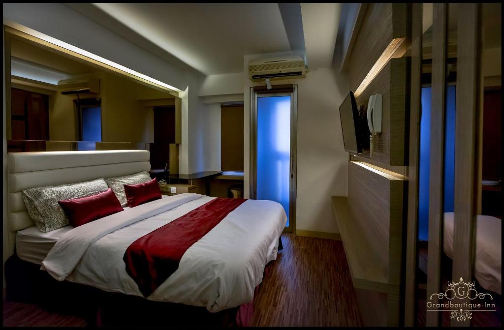 a bedroom with a bed with red pillows and a tv at Grandboutique-Inn in Jakarta