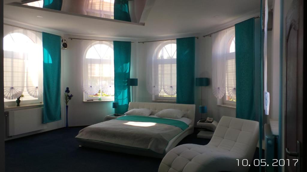 a bedroom with a bed and a chair and windows at Hotel Restauracja Venus in Moderówka