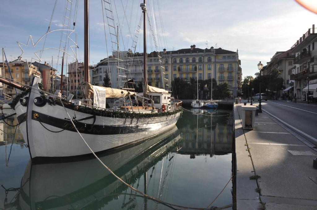 a boat is docked in the water next to a street at Hotel Metropole in Grado