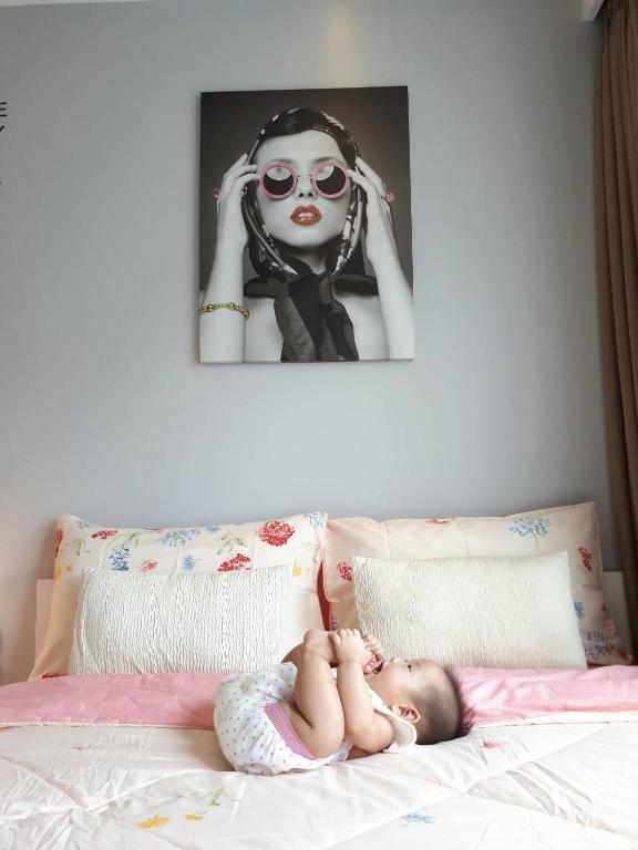 a baby laying on a bed with a picture of a woman at The Trust Huahin By Sopida in Hua Hin