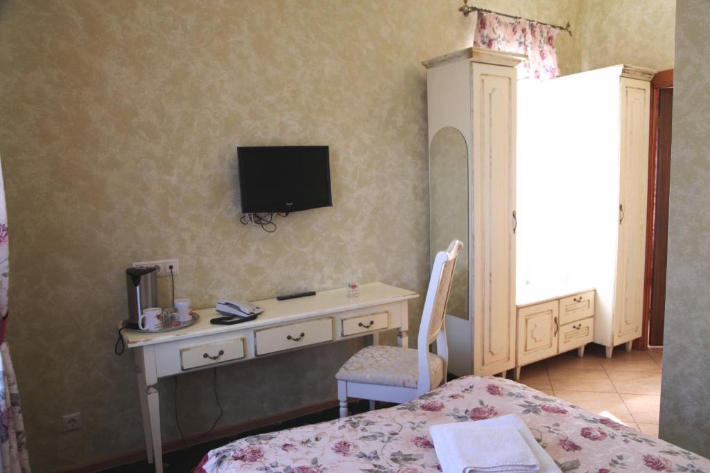 een slaapkamer met een bureau en een tv aan de muur bij Dobr Zdravich in Oefa