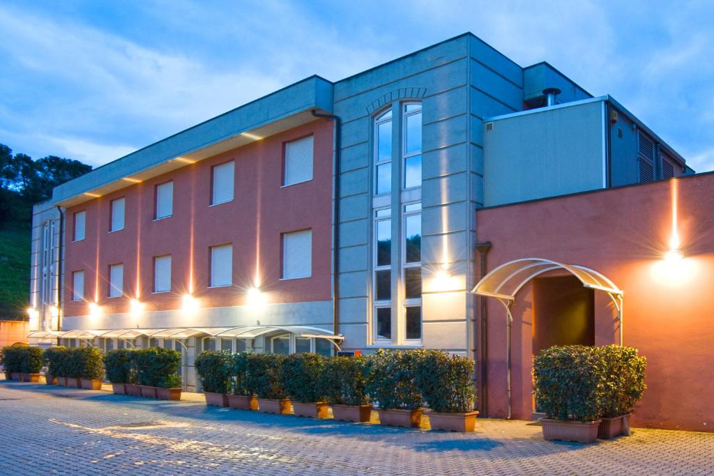 un grand bâtiment avec des buissons devant lui dans l'établissement Hotel Il Viandante, à Terranuova Bracciolini