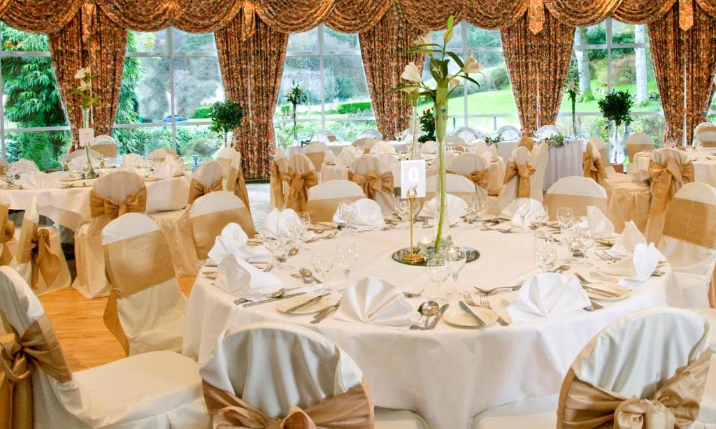 una sala per banchetti nuziali con tavoli e sedie bianchi di The Glendalough Hotel a Laragh
