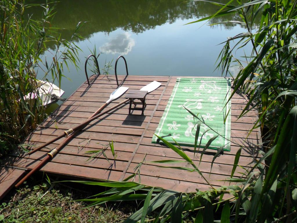 a wooden deck with a table and chairs on the water at Ikerdió faházikó in Szarvas