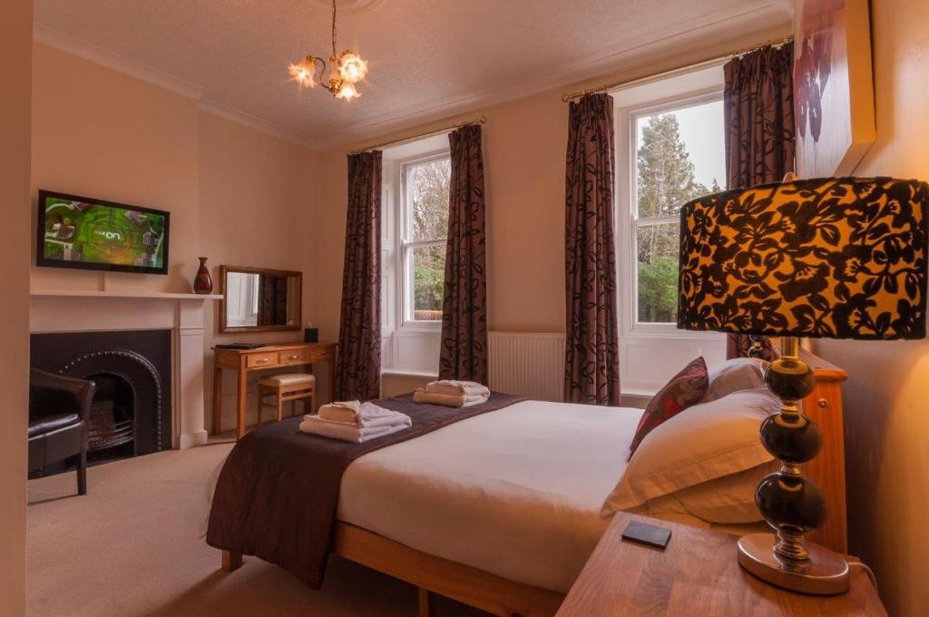 a bedroom with a bed and a fireplace and windows at Powe House in Keswick
