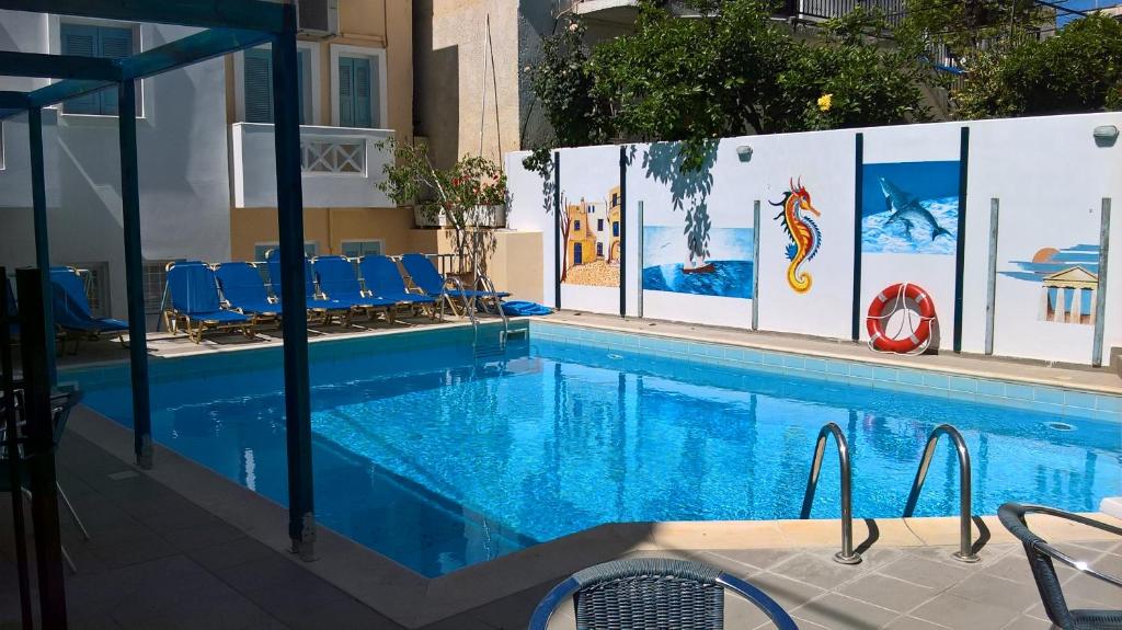 a large swimming pool with blue chairs next to it at Renia Studios - Pool & Beach in 150m - Agia Pelagia in Agia Pelagia