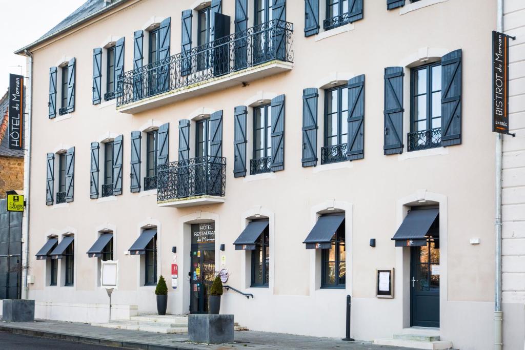 a facade of a white building with black awnings at Hôtel du Morvan in Luzy