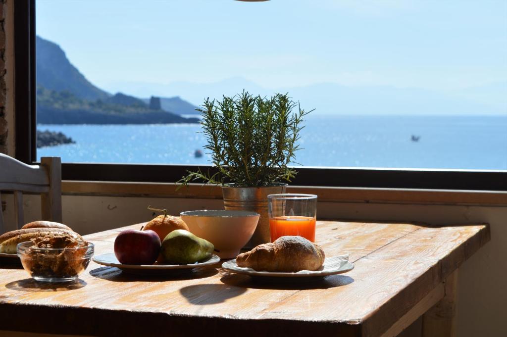 a wooden table with plates of food and a window at Albergo Tirreno in Marina di Camerota