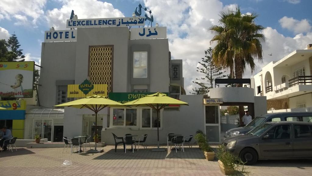 un hôtel avec des tables et des parasols dans un parking dans l'établissement Hotel Excellence, à Tunis