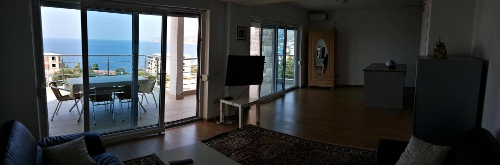 a living room with a balcony with a table and a television at Villa Dobre Vode in Dobra Voda