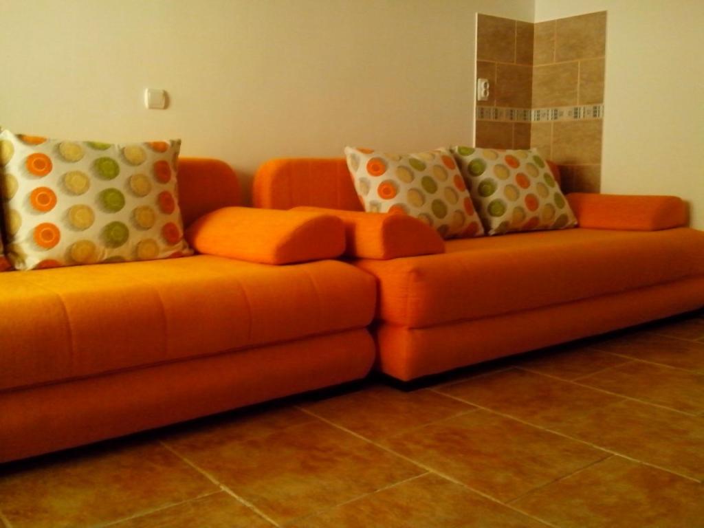 an orange couch with pillows on it in a room at VASILIJA, studio apartman in Budva