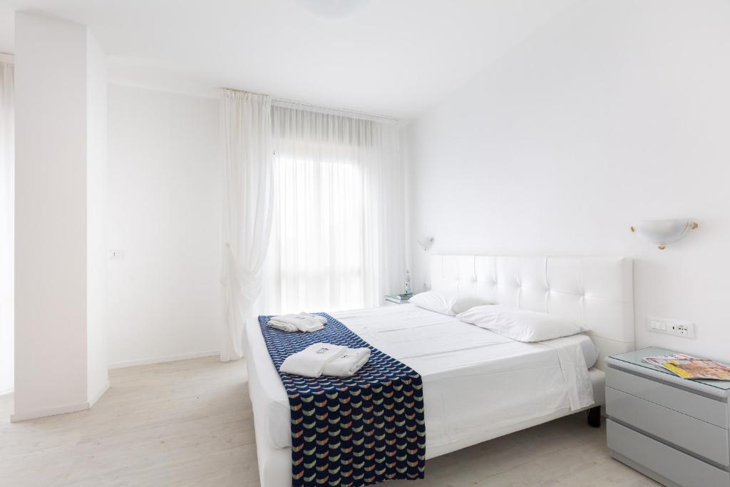 a white bedroom with a bed with two towels on it at Hotel Cavallino Bianco in Cavallino-Treporti