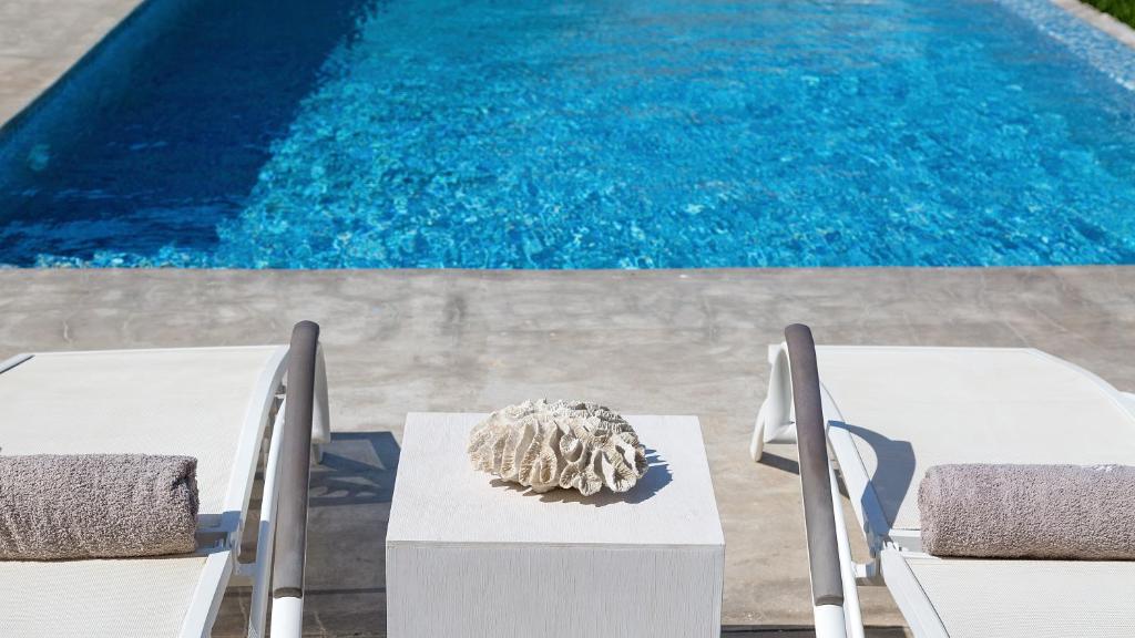 a table and chairs next to a swimming pool at Mykonos Panormos Villas in Mykonos