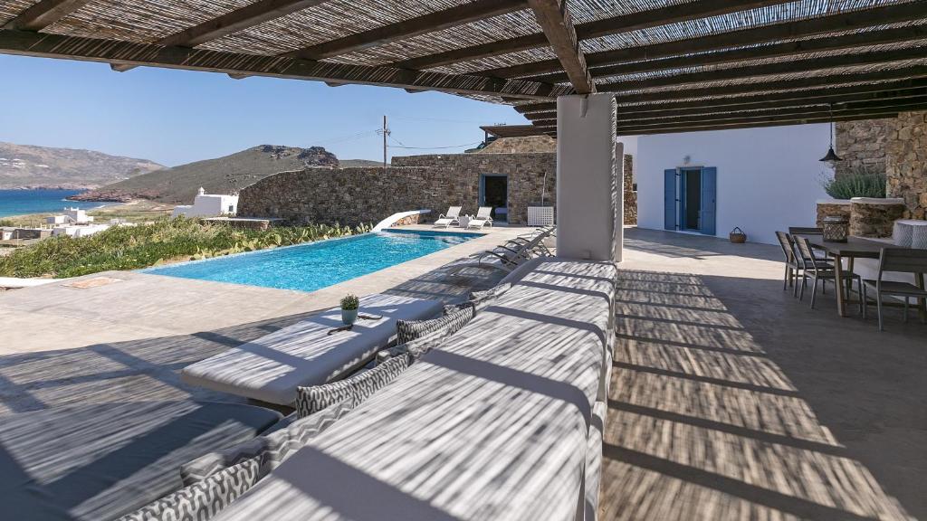 a patio with a pool and a table and chairs at Mykonos Panormos Villas in Mykonos