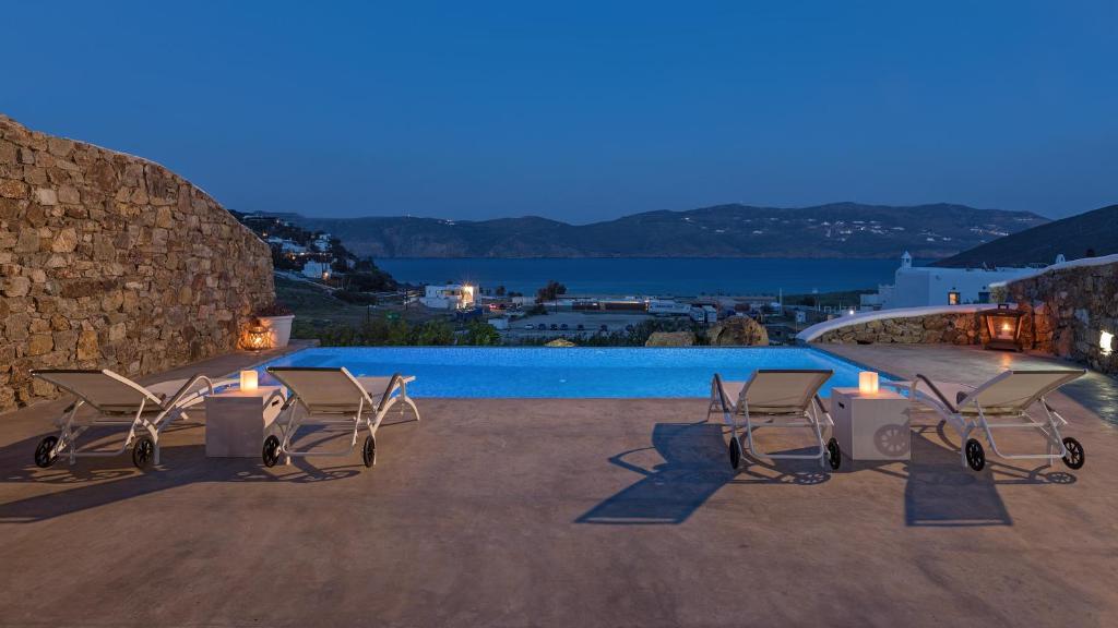 a group of chairs sitting next to a swimming pool at Mykonos Panormos Villas in Mykonos