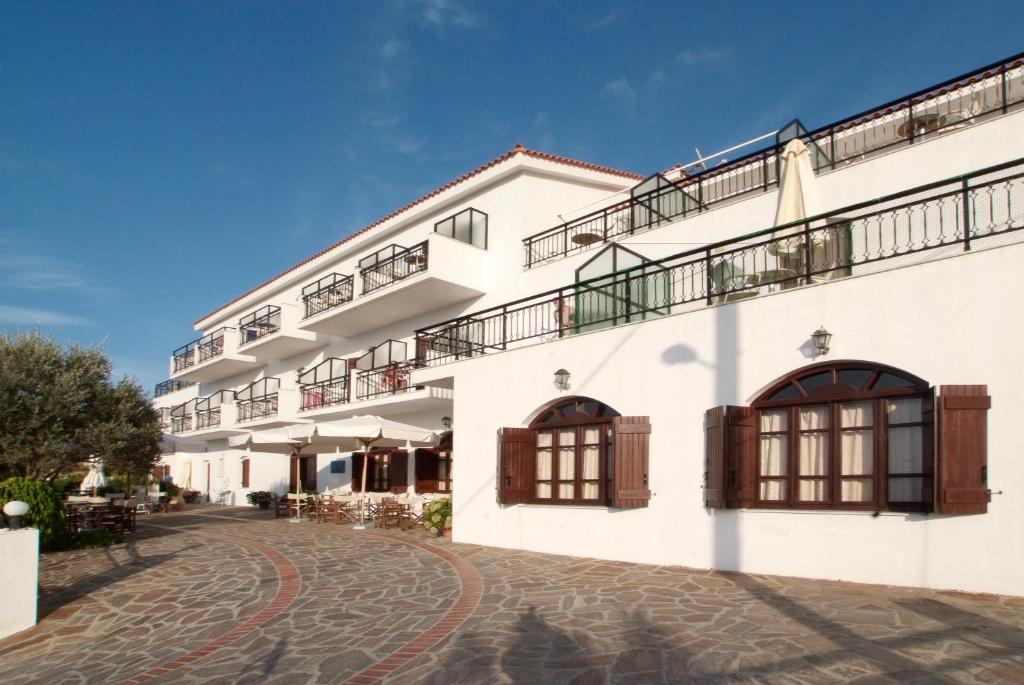 a white building with windows and a cobblestone street at Ikaros Star Hotel in Gialiskari