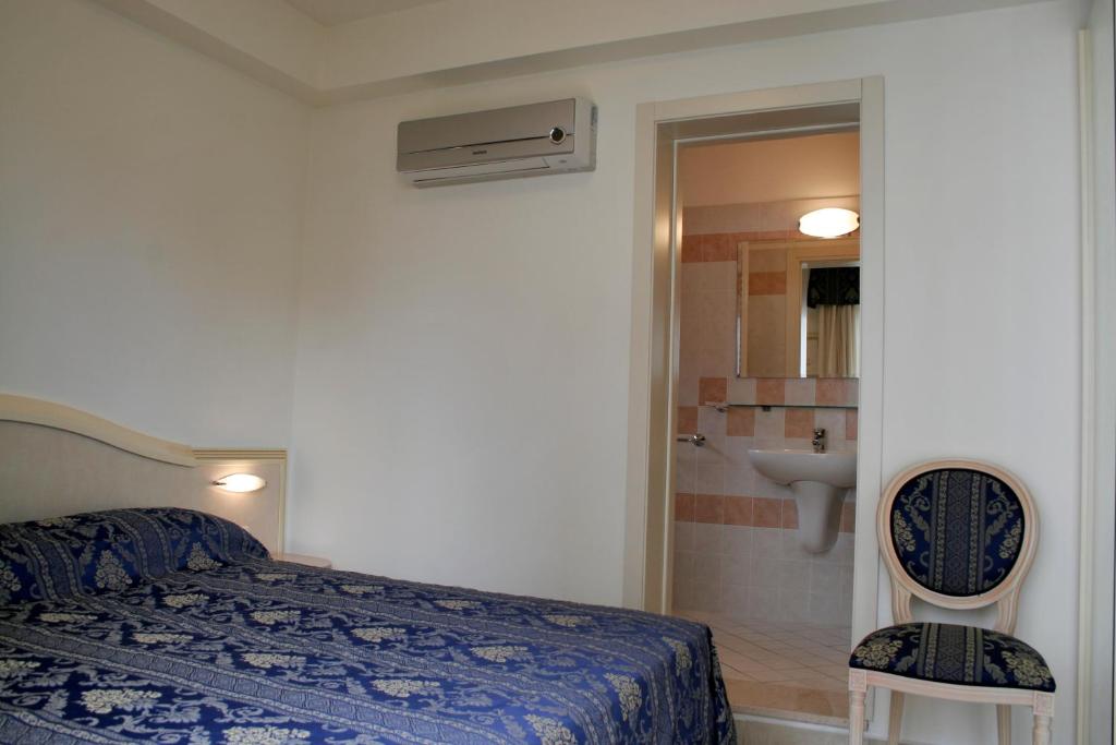 ein Schlafzimmer mit einem Bett und ein Badezimmer mit einem Waschbecken in der Unterkunft Residence Olimpo in Rimini