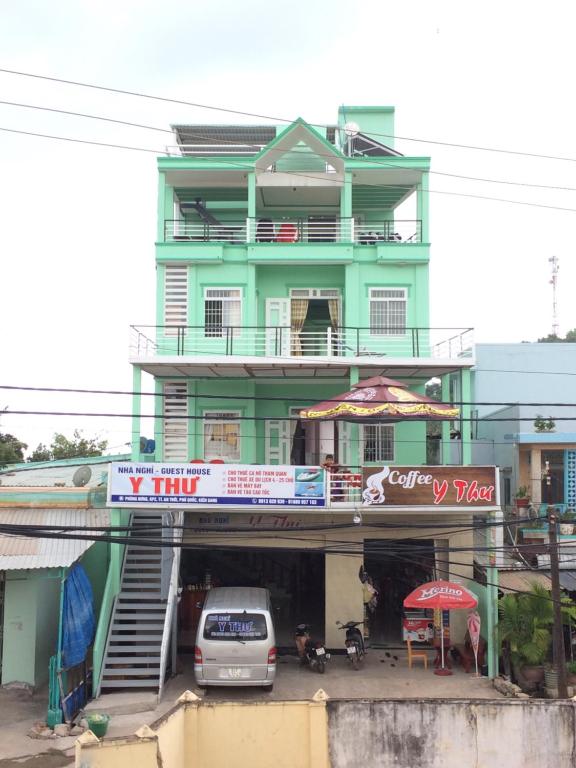 ein grünes Gebäude mit einem davor geparkt in der Unterkunft Y Thu Guesthouse in Phu Quoc