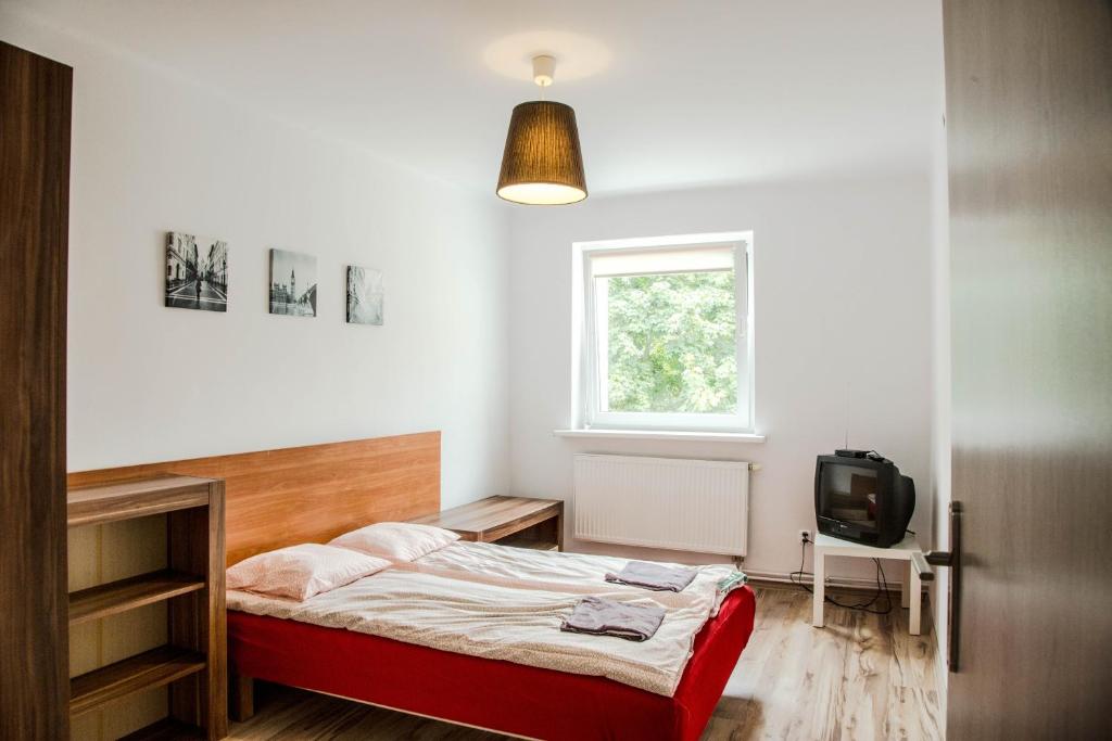 een kleine slaapkamer met een bed en een televisie bij Apartament Centrum Harcerska in Gdynia