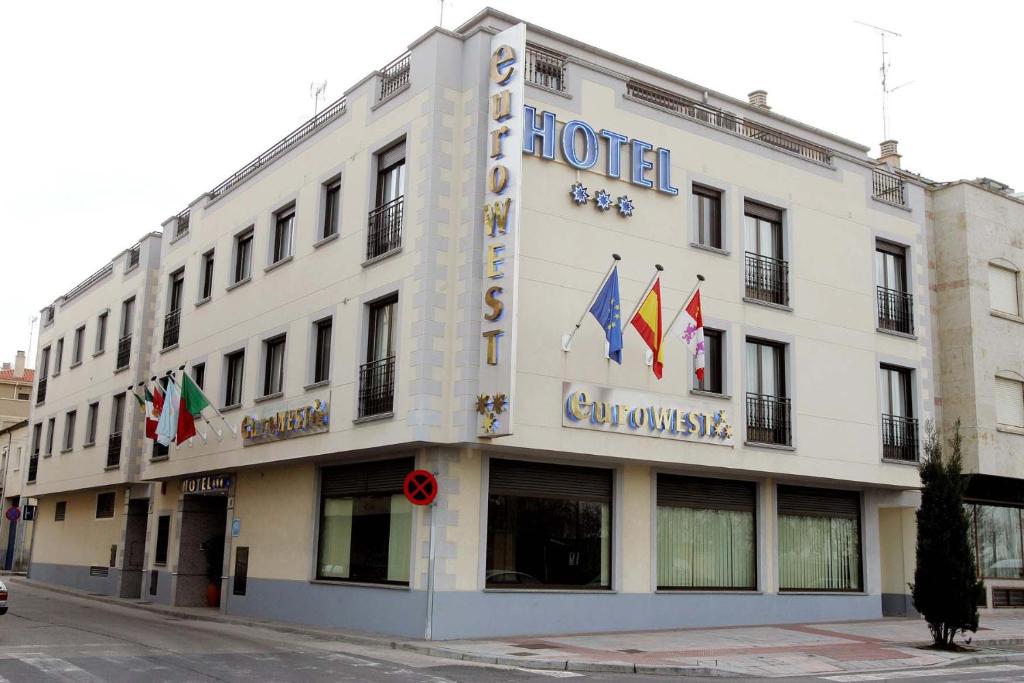 un bâtiment blanc avec des drapeaux sur son côté dans l'établissement Hotel Eurowest, à Salamanque