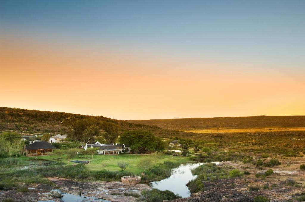 a house in the middle of a field with a river at Bushmans Kloof Wilderness Reserve and Wellness Retreat in Clanwilliam