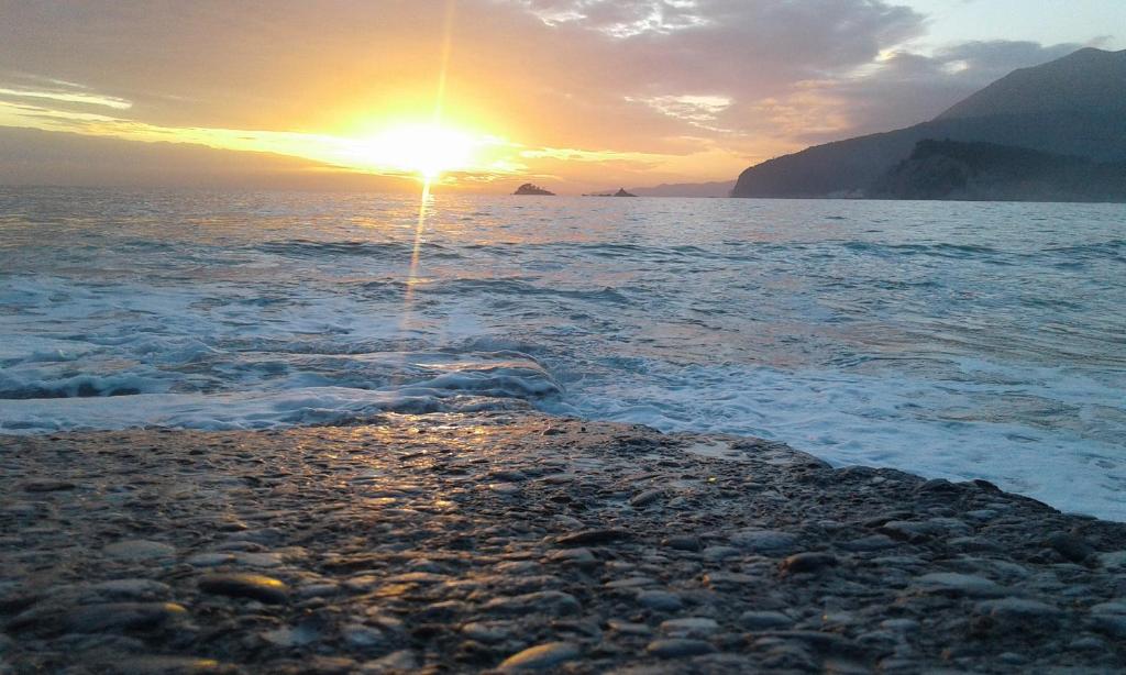 a sunset over the ocean with the sun setting at Buljarica Bay Apartments in Petrovac na Moru