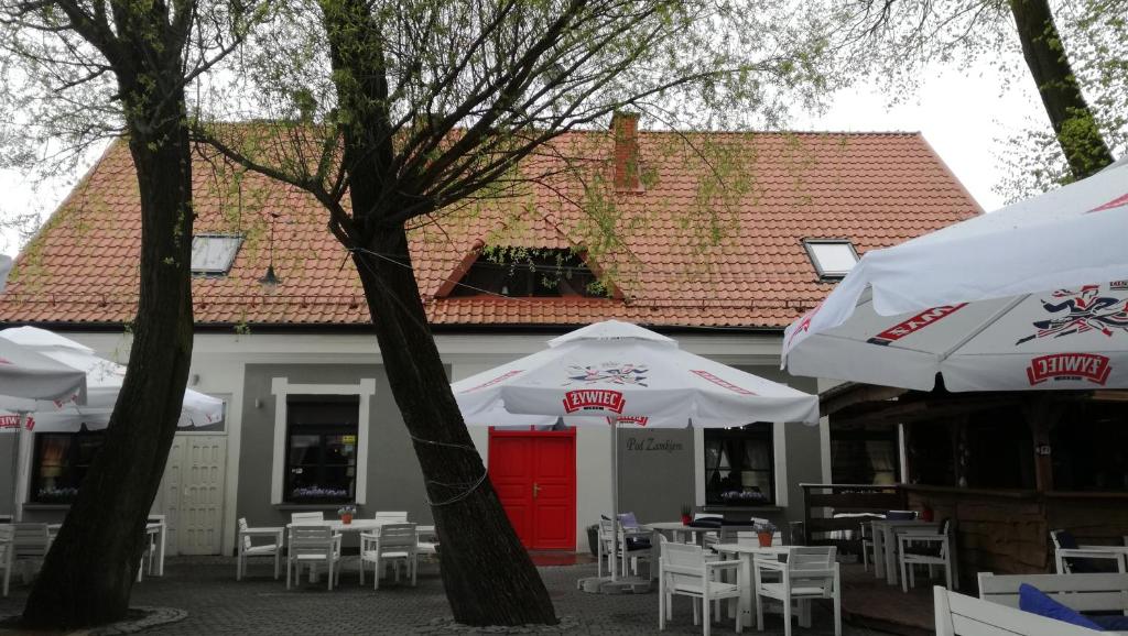 a restaurant with tables and umbrellas in front of a building at Zajazd pod Zamkiem in Kętrzyn