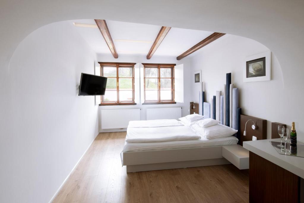 a white bedroom with a bed and a window at Hotel 100 in Pardubice
