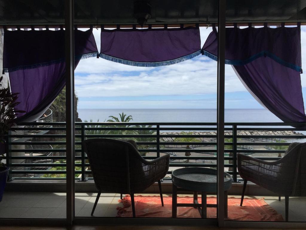 a view of the ocean from a room with chairs and a window at Rocha Mar 3M in Ribeira Brava