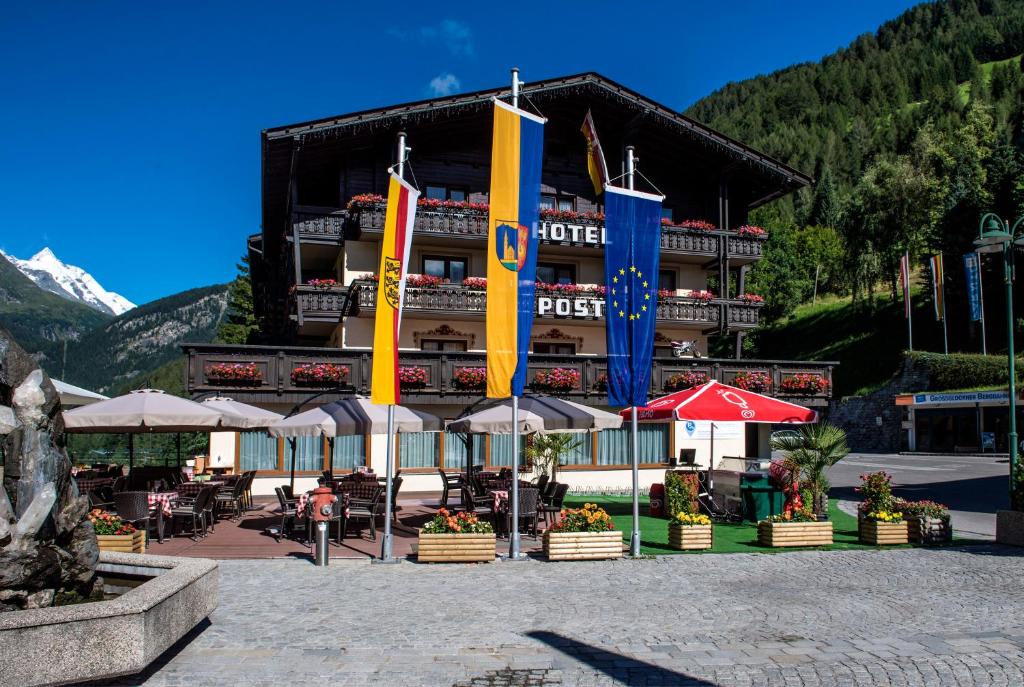 ein Hotel mit Flaggen vor einem Gebäude in der Unterkunft Landhotel Post in Heiligenblut