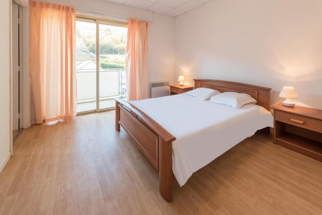 1 dormitorio con cama grande y ventana grande en City Résidence Termalia en Capvern