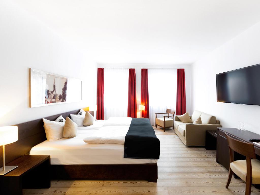 a hotel room with a bed and a couch at DORMERO Hotel Kelheim in Kelheim