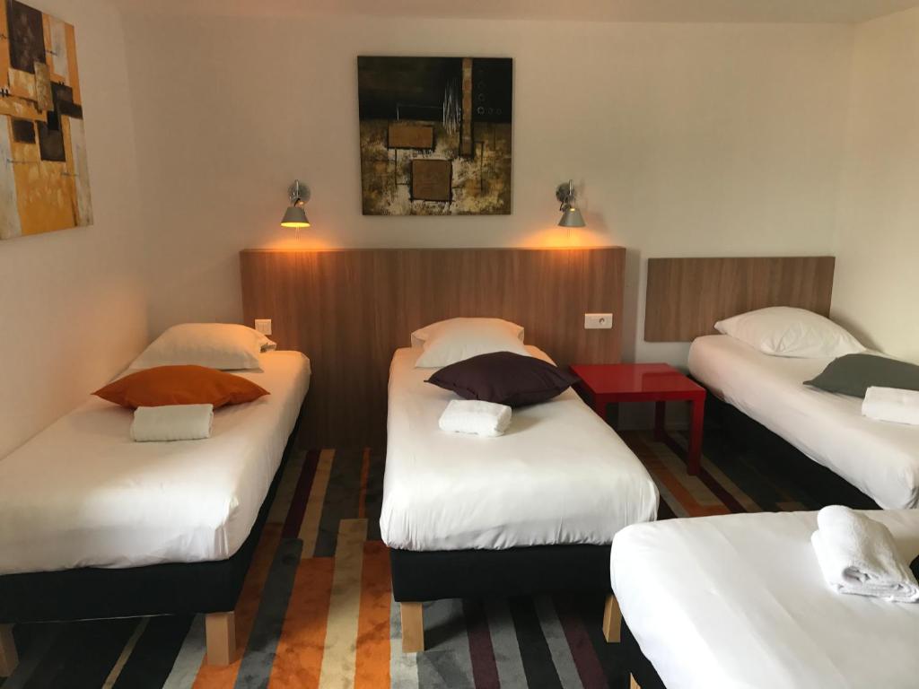 een hotelkamer met drie bedden in een kamer bij Kyriad Direct Agen in Castelculier