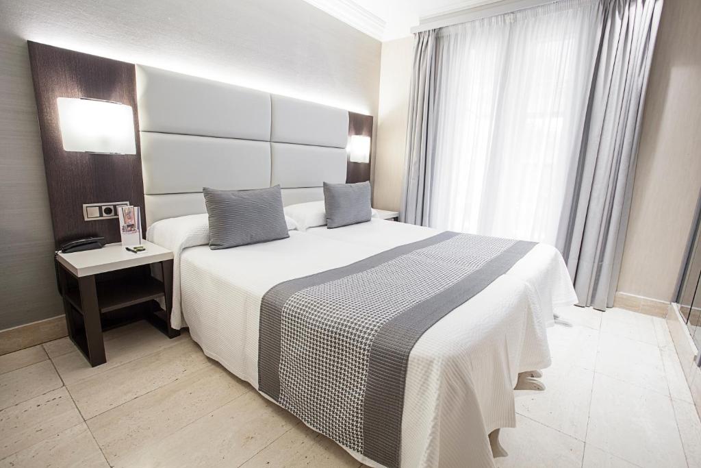 una camera da letto con un grande letto bianco e una finestra di Hotel Europa a Pamplona