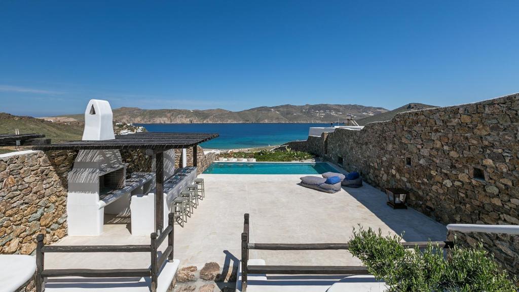 a villa with a swimming pool next to the ocean at Mykonos Panormos Villas in Mykonos