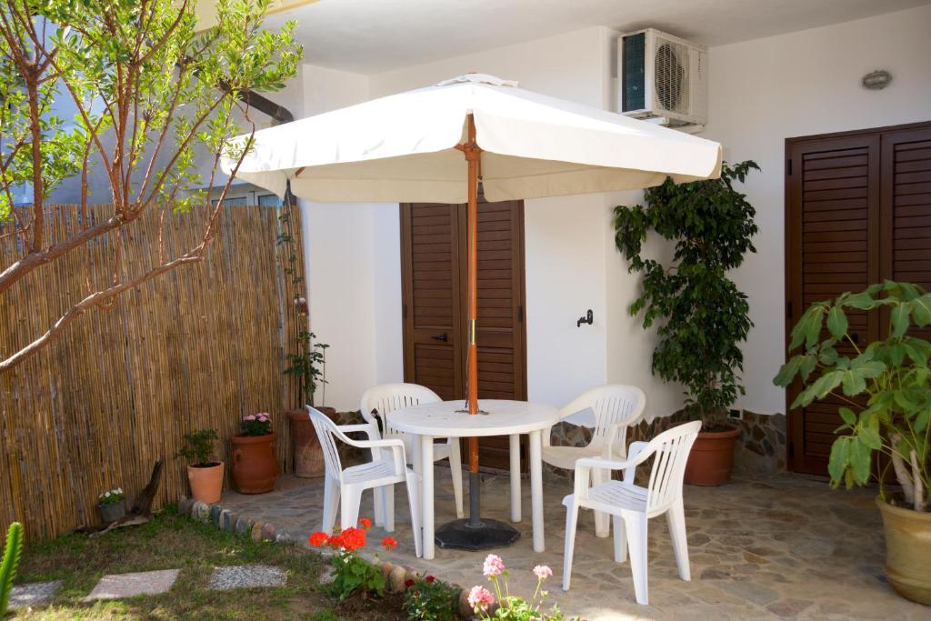 une table et des chaises blanches sous un parasol dans l'établissement Apartment Rose e Fiori Sardegna, à San Vito