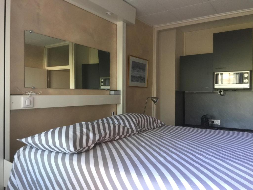 a bedroom with a bed with a striped pillow and a mirror at Fréjus Studio in Fréjus