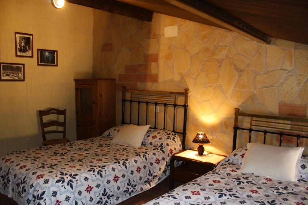 a bedroom with two beds and a stone wall at CASA FAÑETE in Ruguilla
